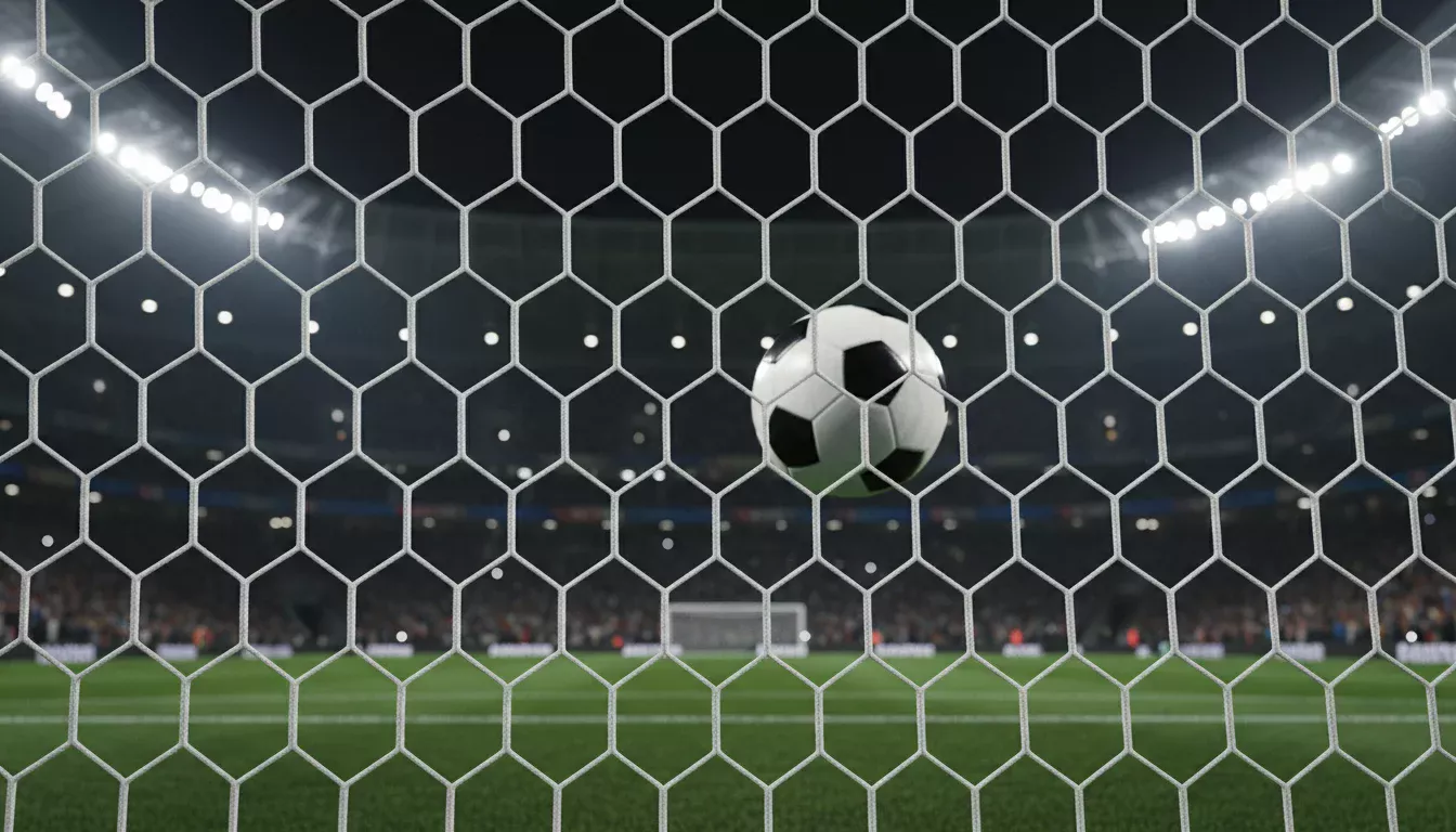 Balón de fútbol entrando en la red de una portería bajo los focos del estadio
